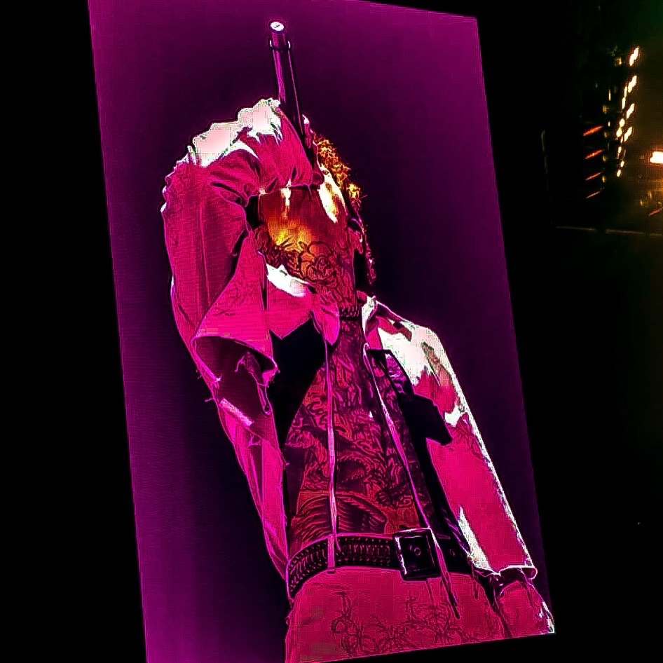 A dynamic performer singing into a microphone on stage, depicted with an artistic filter highlighting vibrant pink and purple colors.