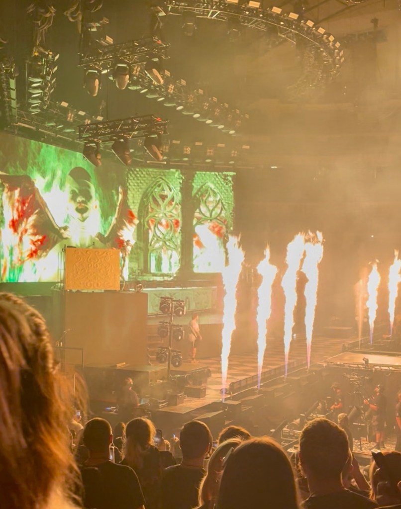 Concert scene featuring a lively performance with dynamic lighting and pyrotechnics, showcasing an engaged audience.